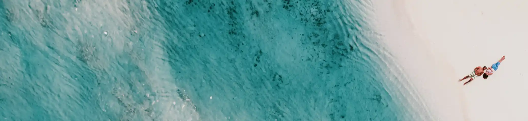 Unico_BannerPubli_Pareja tumbada en playa.webp - Pangea Viajes